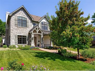 Charming stone-clad two-story home with a well-manicured lawn, mature trees, and beautiful landscaping at 852 Pontiac St, Denver, CO 80220