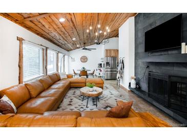 Comfortable living room featuring a large sectional sofa, wood ceiling, and a fireplace with an integrated television at 9034 Us Highway 285, Morrison, CO 80465