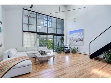 Bright, open living room with soaring ceilings, large windows, and hardwood floors at 3377 Blake St # 205, Denver, CO 80205
