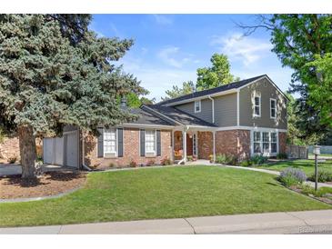 Charming two-story home with brick and siding exterior, mature trees, a well-manicured lawn, and a three car garage at 5081 S Emporia St, Greenwood Village, CO 80111