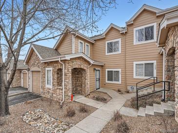 Tan two-story townhome with stone accents, attached garage, and landscaped walkway at 2833 W 119Th Ave # 15-102, Denver, CO 80234