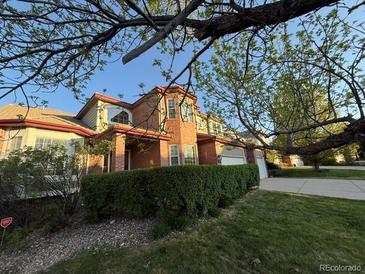 Charming brick home with mature landscaping and a sprawling lawn on a sunny day at 518 Zircon Way, Superior, CO 80027