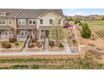Inviting townhome with manicured landscaping, complemented by a white fence and a lush green space at 22898 E Ottawa Pl, Aurora, CO 80016