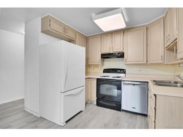 Bright kitchen features wood cabinets, a white refrigerator, and stainless steel dishwasher at 9655 E Center Ave # 9D, Denver, CO 80247