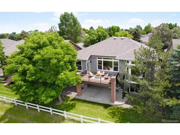 Beautifully landscaped home featuring a spacious deck, spiral staircase, mature trees, and a classic white fence at 1001 Deer Clover Way, Castle Pines, CO 80108