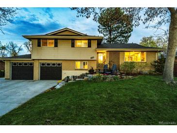 Charming two-story home with a well-manicured lawn, mature tree, and a two car garage at 1140 S Dover St, Lakewood, CO 80232
