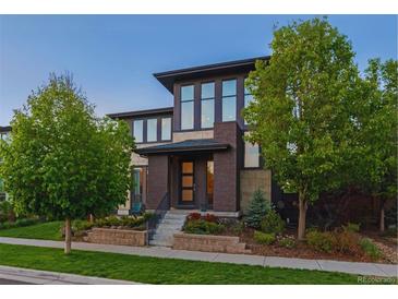 Modern two-story home featuring a manicured lawn, tasteful landscaping, and a stylish brick facade at 8565 E 50Th Dr, Denver, CO 80238