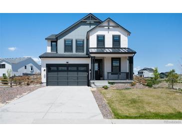 Two-story home boasts a gray and white exterior, attached two-car garage, and a cozy front porch at 1041 W Witherspoon Dr, Elizabeth, CO 80107