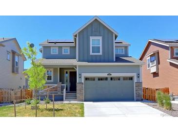 Charming two-story home with blue siding, a two-car garage, and solar panels for energy efficiency at 10983 Uvalda St, Commerce City, CO 80022
