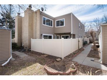 Exterior view of a two-story home featuring a well-maintained backyard with a white fence and partial landscaping at 9695 E Kansas Cir # 44, Denver, CO 80247