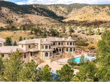 Aerial view showcasing the home's manicured grounds, inviting pool, and stunning mountain backdrop at 6729 Bear Point Trl, Golden, CO 80403