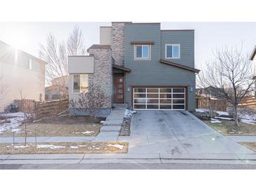 Contemporary two-story home with mixed stone and siding, complemented by a modern glass panel garage door at 10031 Truckee St, Commerce City, CO 80022