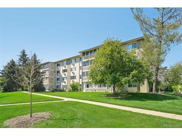 Spacious lawn and sidewalk leading to the well-maintained building under a blue sky with mature trees at 705 S Alton Way # 4D, Denver, CO 80247