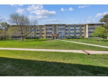 A three-story apartment building featuring well-maintained landscaping and a lush green lawn on a sunny day at 655 S Alton Way # 8D, Denver, CO 80247