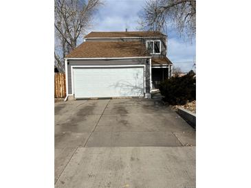 Charming home with two-car garage, gray siding, brown roof, and a large concrete driveway at 11449 E 1St Ave, Aurora, CO 80010