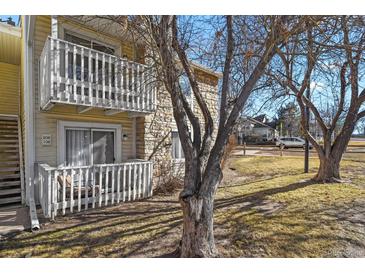 Charming condo with yellow siding, stone accents, and a private balcony overlooking a grassy lawn at 8555 Fairmount Dr # G208, Denver, CO 80247