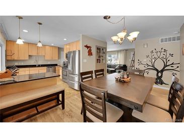 Inviting dining area with wooden table, chairs, and a decorative tree mural for stylish and comfortable gatherings at 12286 W Tennessee Ave, Lakewood, CO 80228