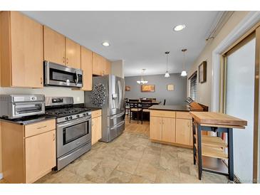 Well-lit kitchen featuring stainless steel appliances, wood cabinets, and an attached dining area at 12286 W Tennessee Ave, Lakewood, CO 80228