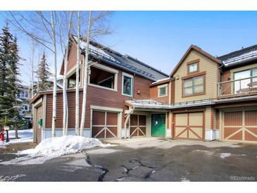 Inviting townhome with multi-car garage, accented by a green entry door and mountain views at 680 S Main St # 18, Breckenridge, CO 80424