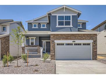 Charming two-story home featuring blue siding, stone accents, and a two-car garage at 683 N Deer Park St, Watkins, CO 80137