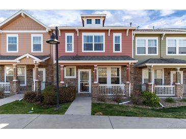 Charming two-story townhouse featuring a cozy front porch with stone accents and well-maintained landscaping at 22725 E Ottawa Pl, Aurora, CO 80016