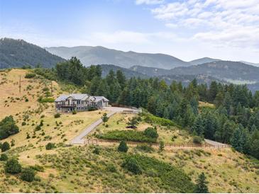 Scenic view of estate-style home with large land parcel nestled on a mountainside surrounded by lush greenery at 18844 Ute Vista Trl, Morrison, CO 80465