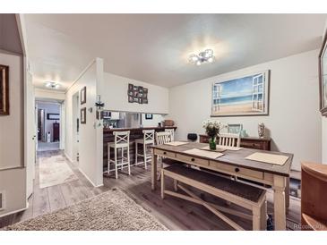 Inviting dining area with a long table, bench, and chairs, complemented by a beach-themed wall art and a bar at 540 S Forest St # 8-101, Denver, CO 80246