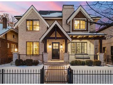 Charming two-story home with a brick facade, black trim windows, a front porch swing, and a wrought iron fence at 2218 S Clayton St, Denver, CO 80210