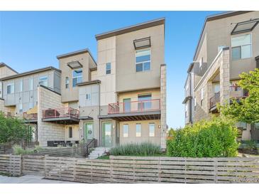 Modern townhome featuring a fenced yard, balcony, and contemporary architectural details at 5668 Galena St, Denver, CO 80238