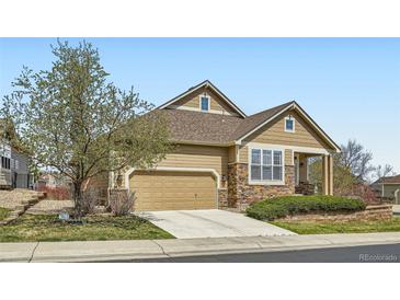 Charming home featuring stone accents, an attached two-car garage, and a well-maintained landscaped front yard at 6642 S Routt St, Littleton, CO 80127