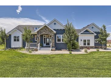 Inviting blue two-story home with a well-manicured lawn and stone entryway at 41975 Muirfield Loop, Elizabeth, CO 80107
