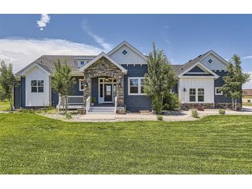 Charming home featuring a stone-accented entrance, well-manicured lawn, and blue and white color scheme at 41975 Muirfield Loop, Elizabeth, CO 80107