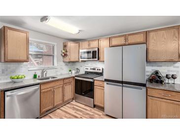 Well-lit kitchen features wood cabinets, stainless steel appliances and granite countertops at 5833 S Pearl St, Centennial, CO 80121