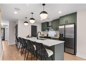 Bright kitchen showcasing a large island with bar seating, matte green cabinets, stainless appliances, and hardwood floors at 3275 Lawrence St, Denver, CO 80205