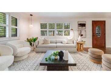 Bright living room with hardwood floors, gray sofa, white armchair, and large window with natural light at 2090 Irving St, Denver, CO 80211