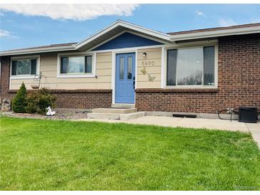 Charming single-story home with a brick and siding exterior, complemented by a well-manicured lawn and a cheerful blue front door at 5690 W 79Th Ave, Arvada, CO 80003