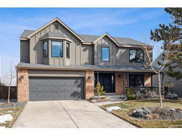 Charming two-story home featuring a brick and siding exterior, attached garage, and inviting front porch at 1711 Spring Water Ln, Highlands Ranch, CO 80129