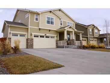 Two-story house with beige siding, stone accents, and a three-car garage at 2521 E 163Rd Pl, Thornton, CO 80602