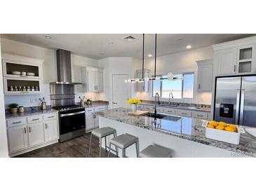 Modern kitchen boasts granite counters, stainless appliances, island with seating and a sleek lighting fixture at 61400 E 56 Ave, Strasburg, CO 80136