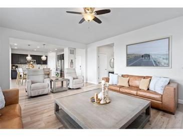 Bright living room featuring hardwood floors, a ceiling fan, a leather couch and contemporary furnishings at 7315 Blue Water Dr, Castle Rock, CO 80108