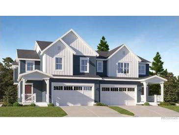 Charming townhome with white and gray exterior, two-car garage, and well-manicured lawn at 577 Nightsky St, Erie, CO 80516