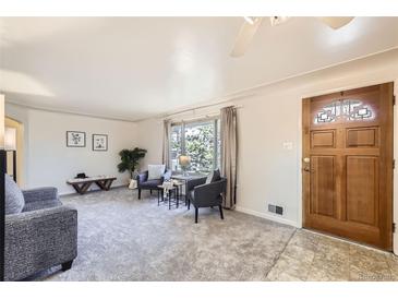 Bright living room features large windows, neutral paint, and plush carpeting at 1495 S Chase Ct, Lakewood, CO 80232