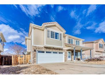 Inviting two-story home featuring stone accents, a two-car garage, and a charming front porch at 15333 E 98Th Pl, Commerce City, CO 80022