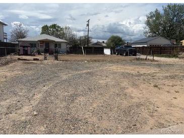 Large gravel backyard with a chain link fence, shed, and detached garage at 6441 Niagara St, Commerce City, CO 80022