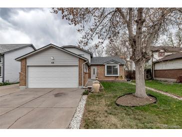 Charming home features a well-kept front yard, mature tree, and attached garage at 45 Pierce St, Lakewood, CO 80226