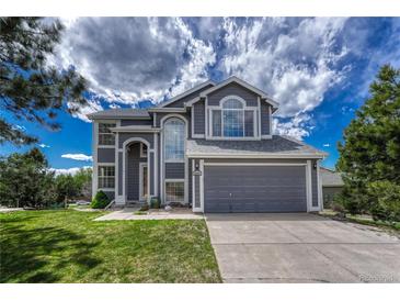 Two-story home with an attached two-car garage and a well-manicured lawn under a cloudy blue sky at 3630 Sawgrass Trl, Castle Rock, CO 80109