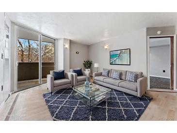 Bright living room featuring modern furnishings, stylish rug, and a sliding glass door to the balcony at 601 W 11Th Ave # 109, Denver, CO 80204