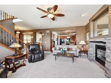 Open living room showcasing a stone fireplace and seamless flow to the kitchen at 2116 Ridgetrail Dr, Castle Rock, CO 80104