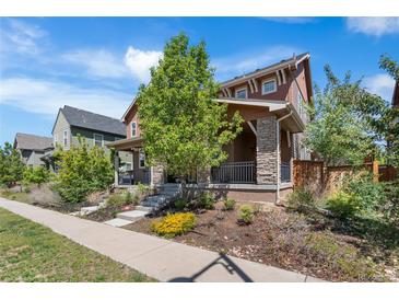 Charming two-story home featuring stone accents, a welcoming porch, and beautifully landscaped front yard at 10859 E 25Th Dr, Aurora, CO 80010