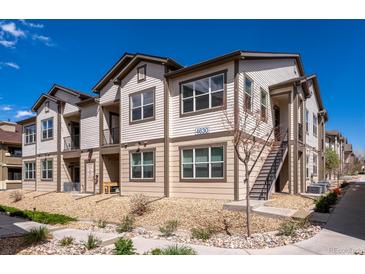Attractive two-story townhome with a light beige exterior, landscaped grounds, and a clear blue sky at 4630 Copeland Cir # 201, Highlands Ranch, CO 80126